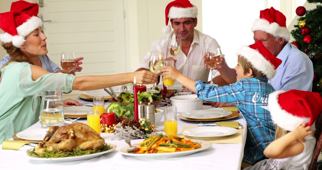 Happy Family Celebrating Christmas Dinner with Toasts and Santa Hats - Free Images, Stock Photos and Pictures on Pikwizard.com