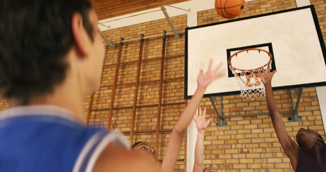 Players reaching for basketball under hoop in gym - Free Images, Stock Photos and Pictures on Pikwizard.com