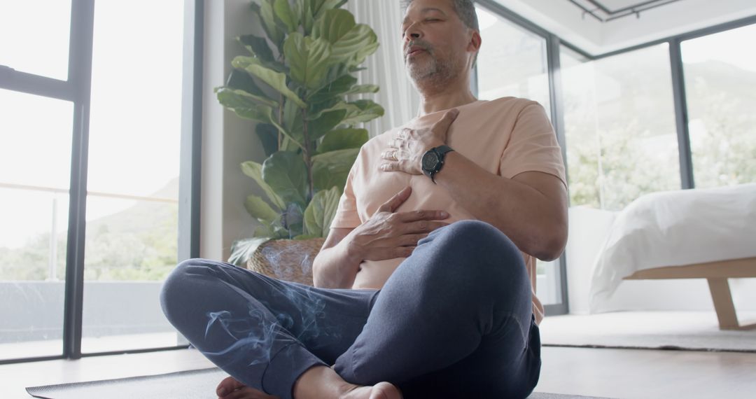 Middle-aged man practicing meditation and deep breathing exercises at home - Free Images, Stock Photos and Pictures on Pikwizard.com