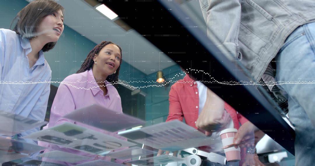 Collaborative team reviewing documents around glass table in modern office meeting