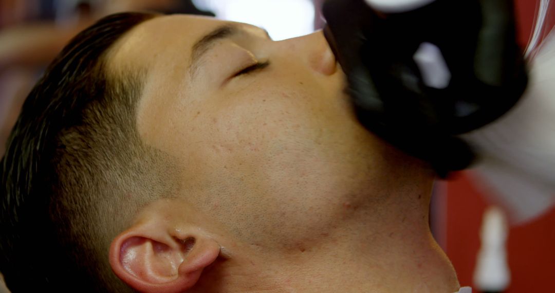 Barber giving close shave to young man - Free Images, Stock Photos and Pictures on Pikwizard.com