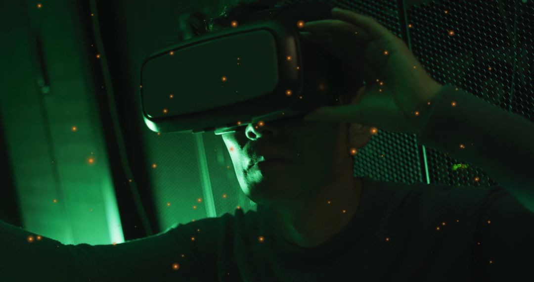 Korean Man Adjusting VR Headset in Green-Lit Room with Ambient Particles