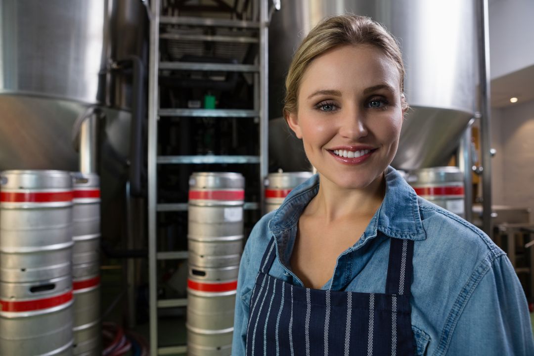 Smiling Female Worker in Brewery with Storage Tanks - Free Images, Stock Photos and Pictures on Pikwizard.com