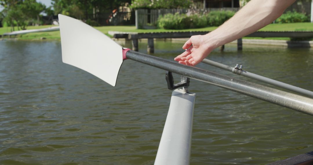 Person Adjusting Rowing Oar by Lake - Free Images, Stock Photos and Pictures on Pikwizard.com