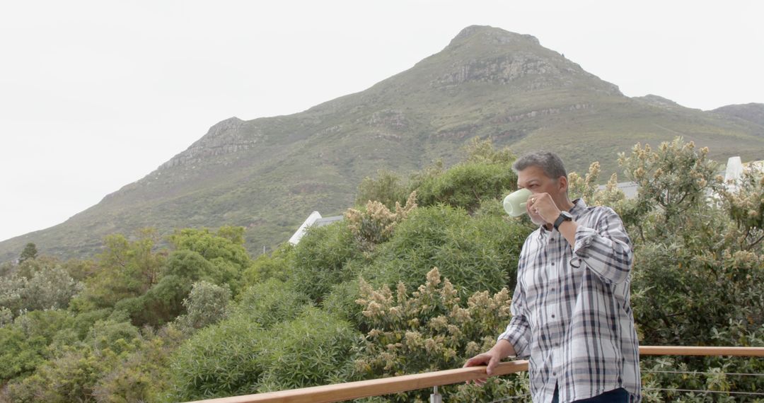 Man Drinking From Cup on Balcony Overlooking Mountain Scenery - Free Images, Stock Photos and Pictures on Pikwizard.com