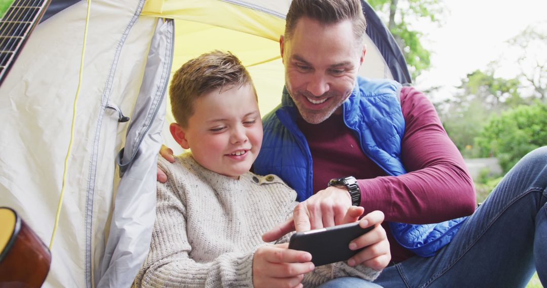 Father and Son Enjoy Outdoor Time with Smartphone in Tent - Free Images, Stock Photos and Pictures on Pikwizard.com