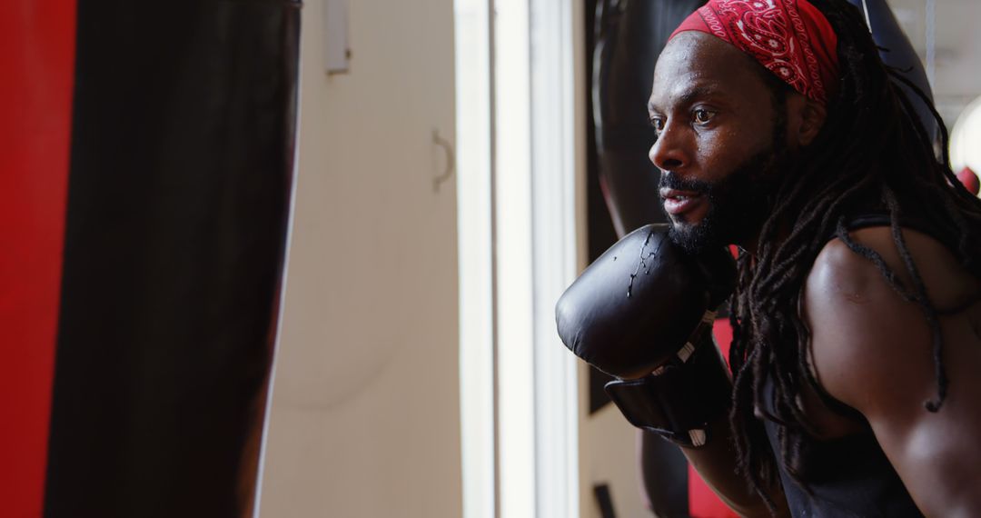 Dedicated Black Man Punching Bag in Gym with Red Bandana - Free Images, Stock Photos and Pictures on Pikwizard.com