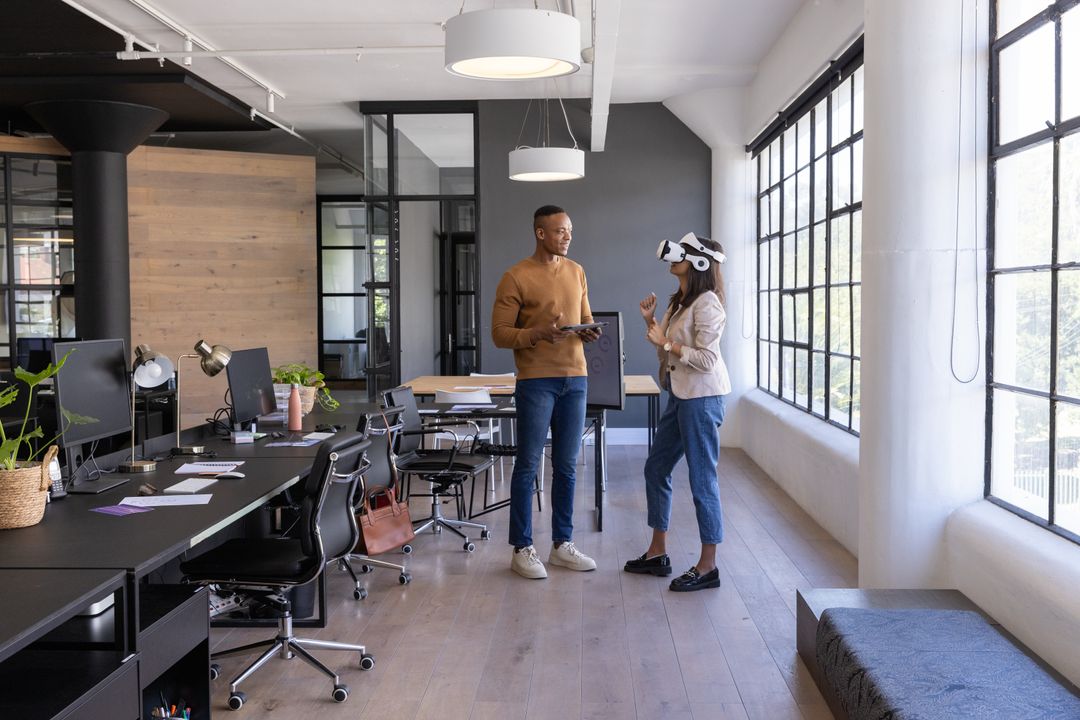 Diverse coworkers collaborating with VR headset and tablet in modern open-plan office