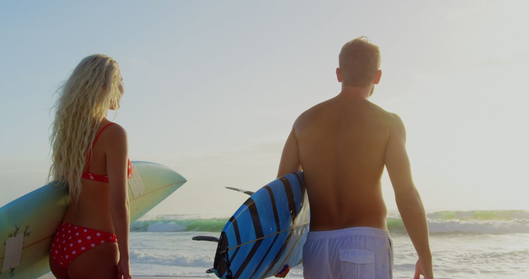 Surfer Couple Watching Ocean on Sunlit Beach