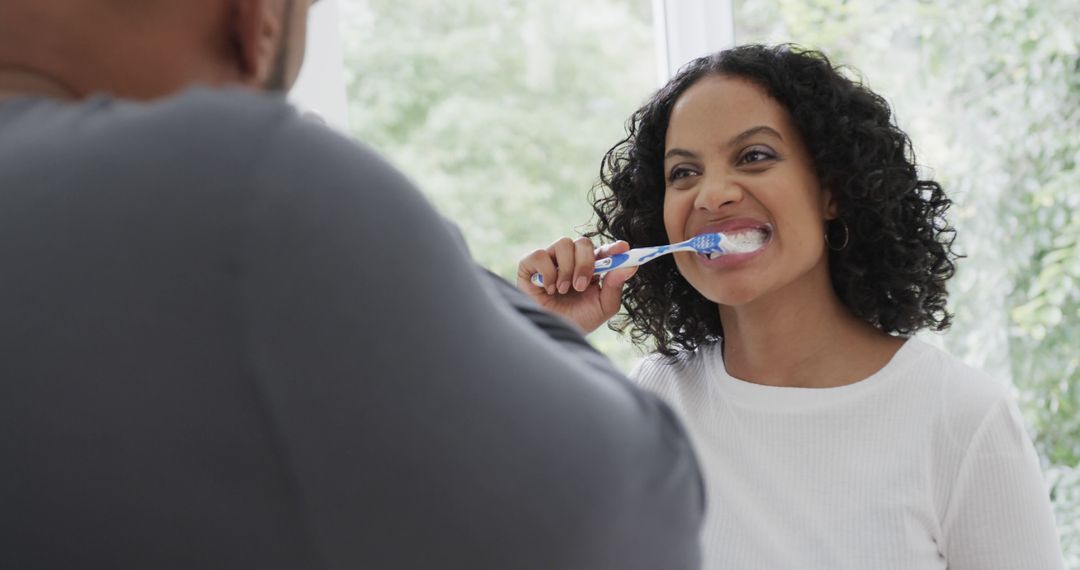 Smiling Woman Brushing Teeth While Partner Watches - Free Images, Stock Photos and Pictures on Pikwizard.com