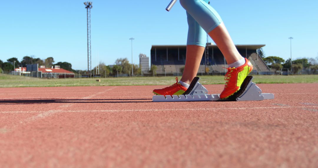 Athlete Preparing for Sprint with Baton on Track Field - Free Images, Stock Photos and Pictures on Pikwizard.com