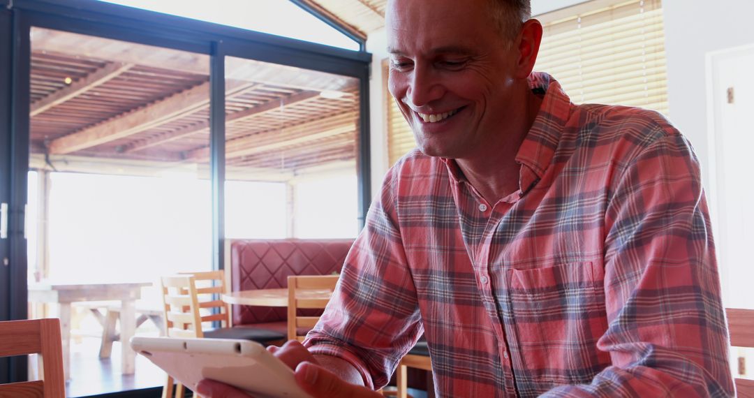 Smiling man using digital tablet in modern cafe - Free Images, Stock Photos and Pictures on Pikwizard.com