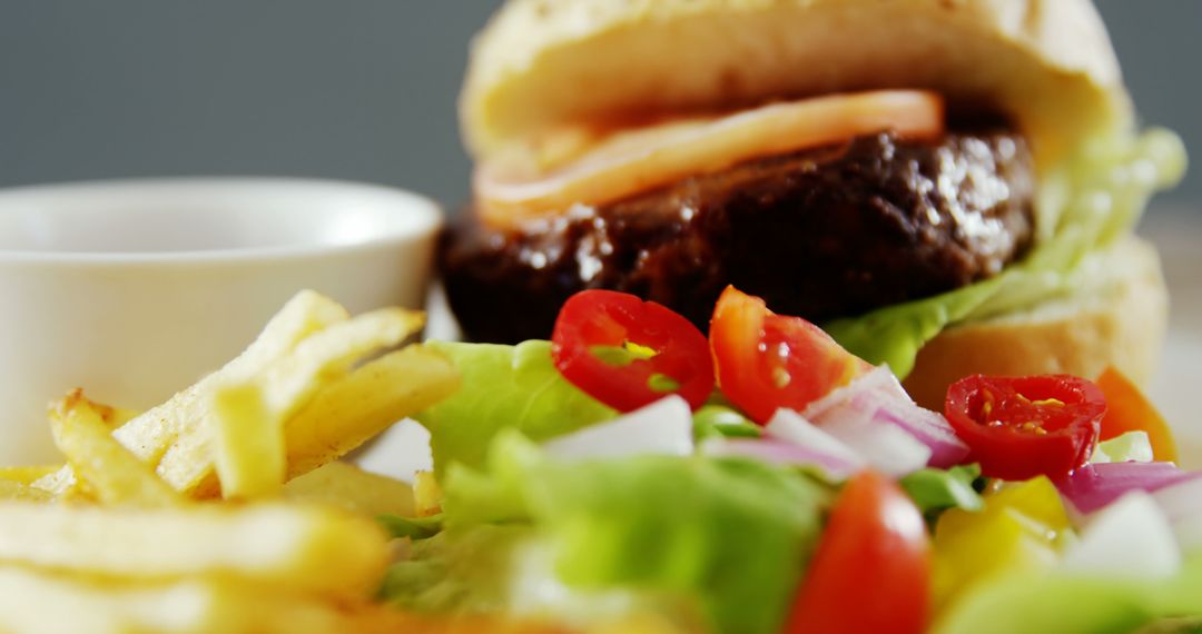 Close-up View of Juicy Burger with Fries and Fresh Vegetables - Free Images, Stock Photos and Pictures on Pikwizard.com