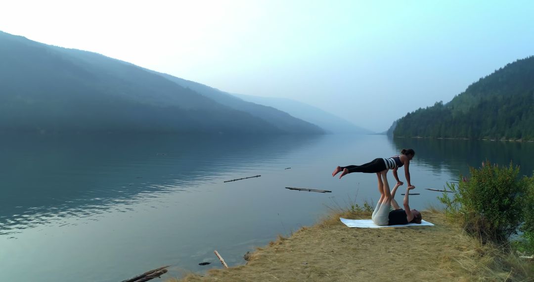 Couple Practicing Acroyoga by Serene Lake and Forested Hills - Free Images, Stock Photos and Pictures on Pikwizard.com