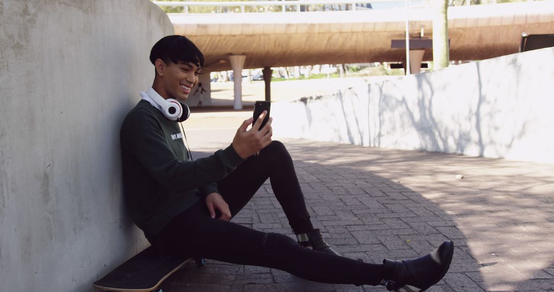 Young man sitting on skateboard outdoors taking selfie with smartphone - Free Images, Stock Photos and Pictures on Pikwizard.com