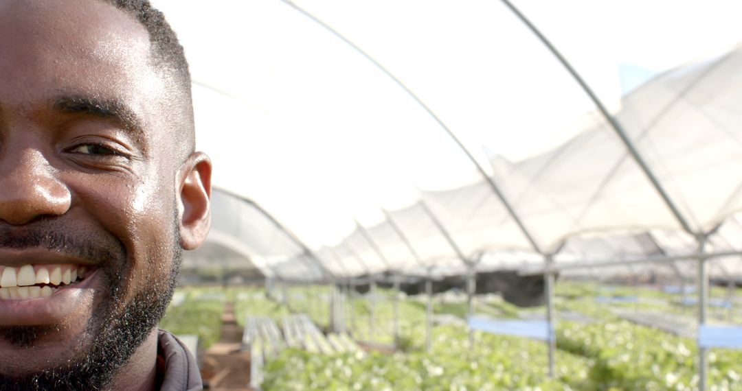 Smiling Man in Greenhouse Showcasing Sustainable Farming Practices