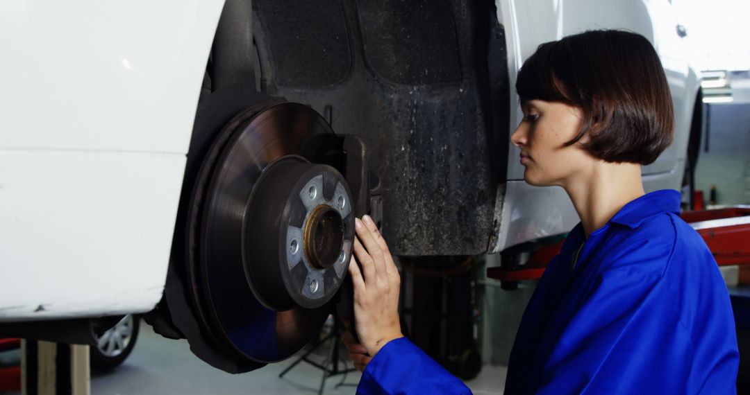 Female mechanic inspecting car brake system in garage - Free Images, Stock Photos and Pictures on Pikwizard.com