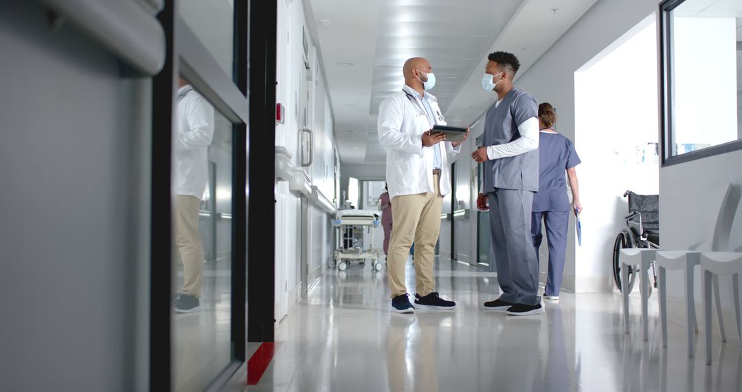 Doctors Consulting in a Bright Hospital Corridor - Free Images, Stock Photos and Pictures on Pikwizard.com