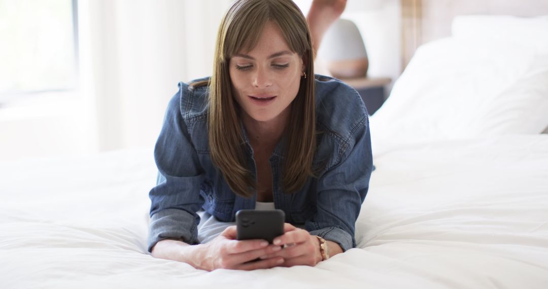 Woman Relaxing with Smartphone on Bed in Casual Home Setting