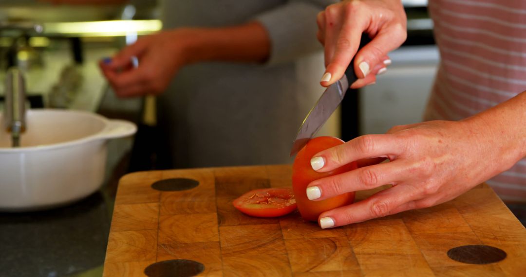 Person Slicing Tomato on Wooden Cutting Board in Kitchen - Free Images, Stock Photos and Pictures on Pikwizard.com