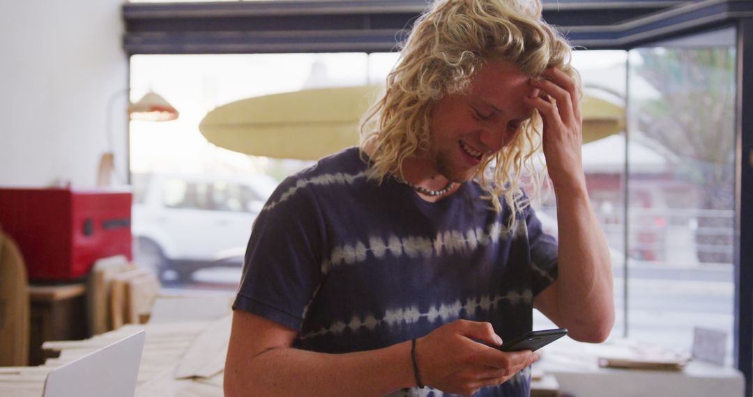 Smiling Young Man Using Smartphone in Surf Shop - Free Images, Stock Photos and Pictures on Pikwizard.com