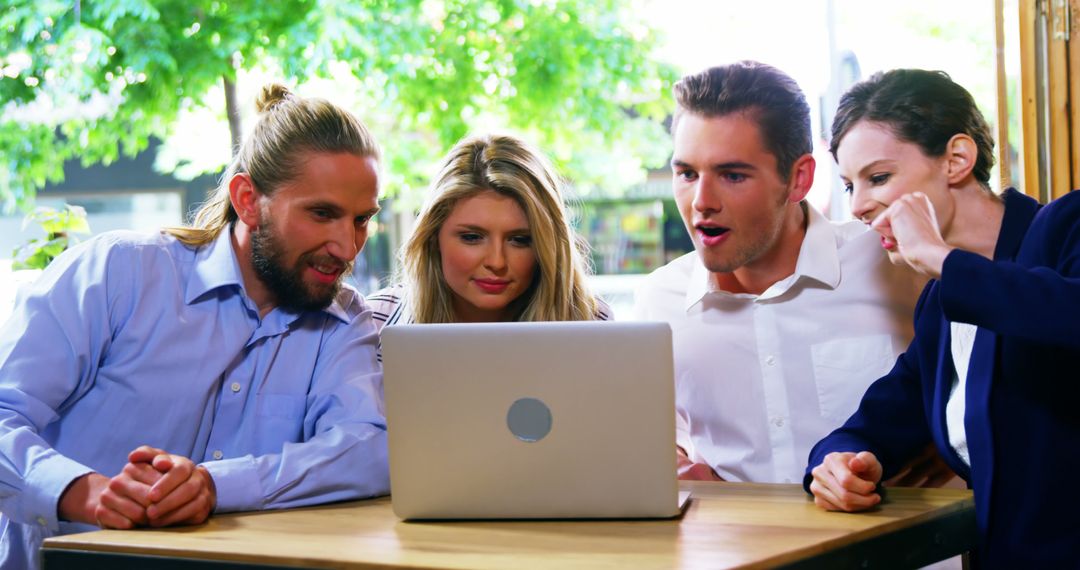 Group of Friends Engaged with Laptop in Outdoor Cafe