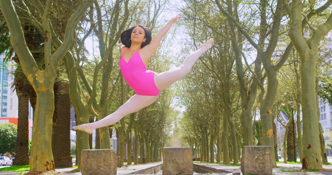 Graceful Ballerina Leaping in Tree-Lined Park with Sunlight