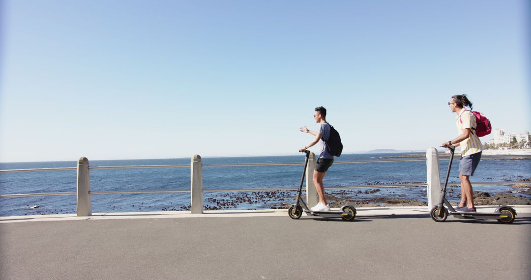 Two Individuals Riding Electric Scooters Along Seaside Path - Free Images, Stock Photos and Pictures on Pikwizard.com