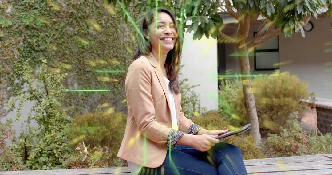 Asian professional woman smiling and holding tablet while sitting on courtyard bench
