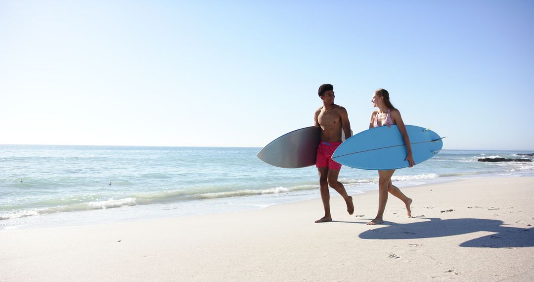 Diverse Couple Strolling with Surfboards on Sunny Beach