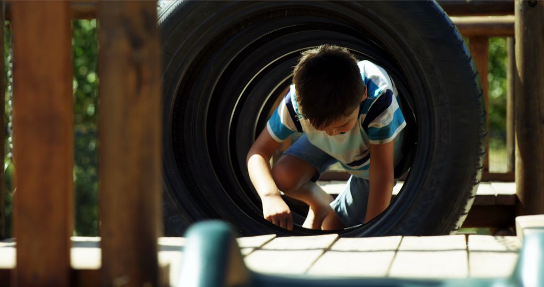 Boy playing in oversized tire on playground - Free Images, Stock Photos and Pictures on Pikwizard.com