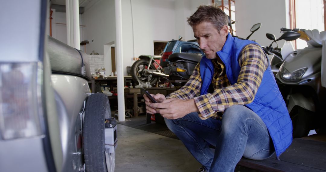 Mechanic Checking Phone in Auto Repair Garage - Free Images, Stock Photos and Pictures on Pikwizard.com