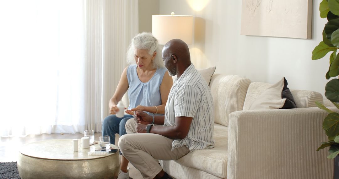 Senior Couple Organizing Medication Together on Sofa in Bright Room
