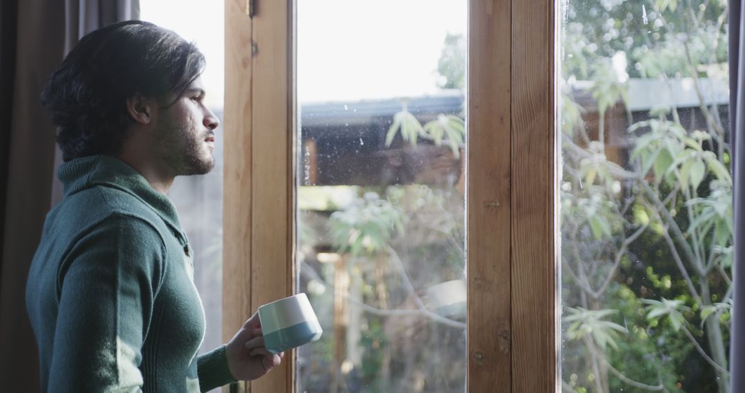 Contemplative Man Holding Coffee Mug by Window on Tranquil Morning - Free Images, Stock Photos and Pictures on Pikwizard.com