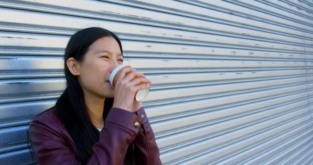 Young Asian Woman Drinking Coffee Outdoors Against Industrial Background - Free Images, Stock Photos and Pictures on Pikwizard.com