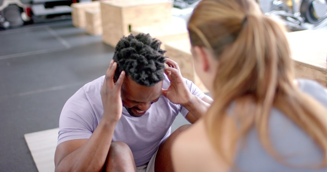 Fit Man Doing Sit-Ups with Encouragement from Personal Trainer at Gym