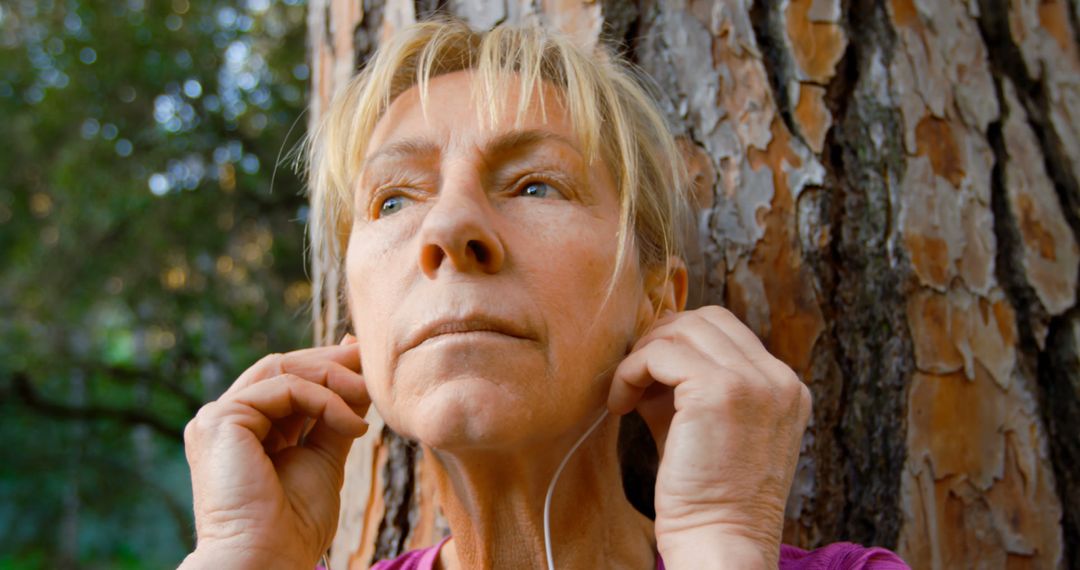 Senior Woman Adjusting Earphones While Resting Outdoors - Free Images, Stock Photos and Pictures on Pikwizard.com