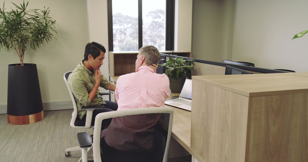 Colleagues Collaborating at Modern Office Desk By Windows