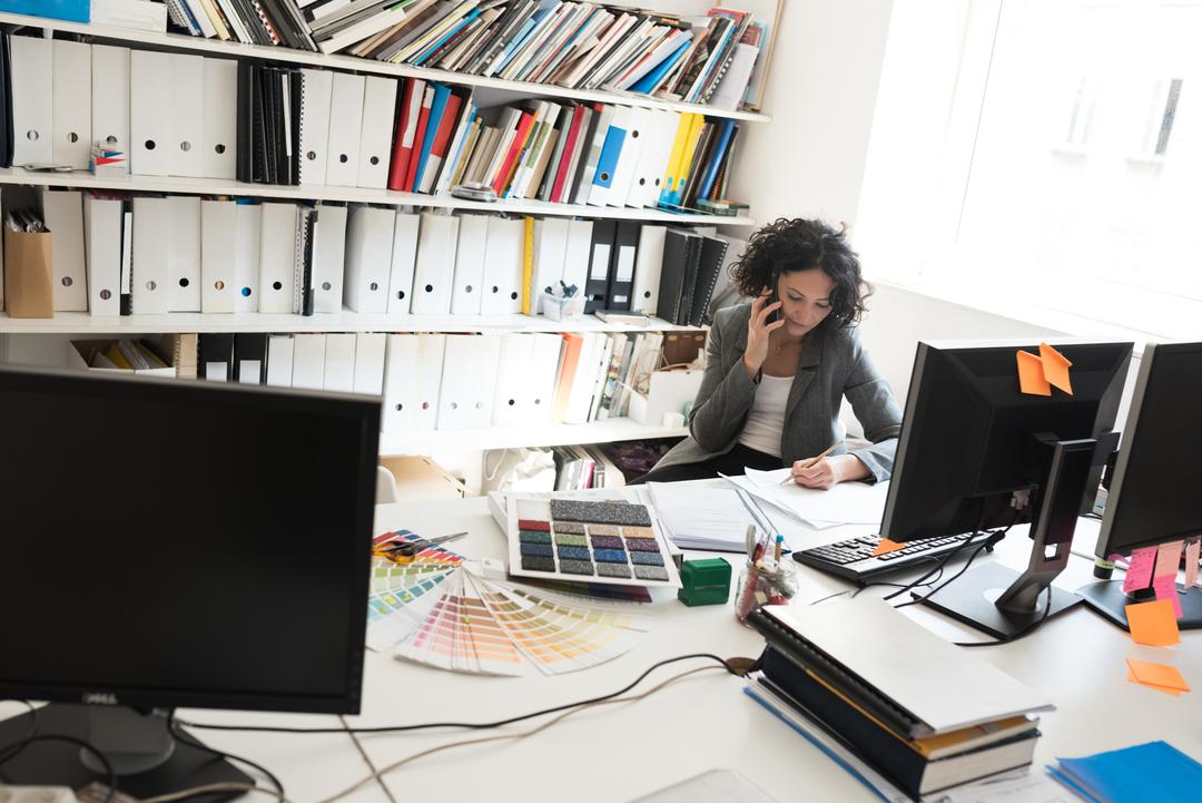 Image of a woman on her phone at her office - Why is it important to verify your social media accounts - Image