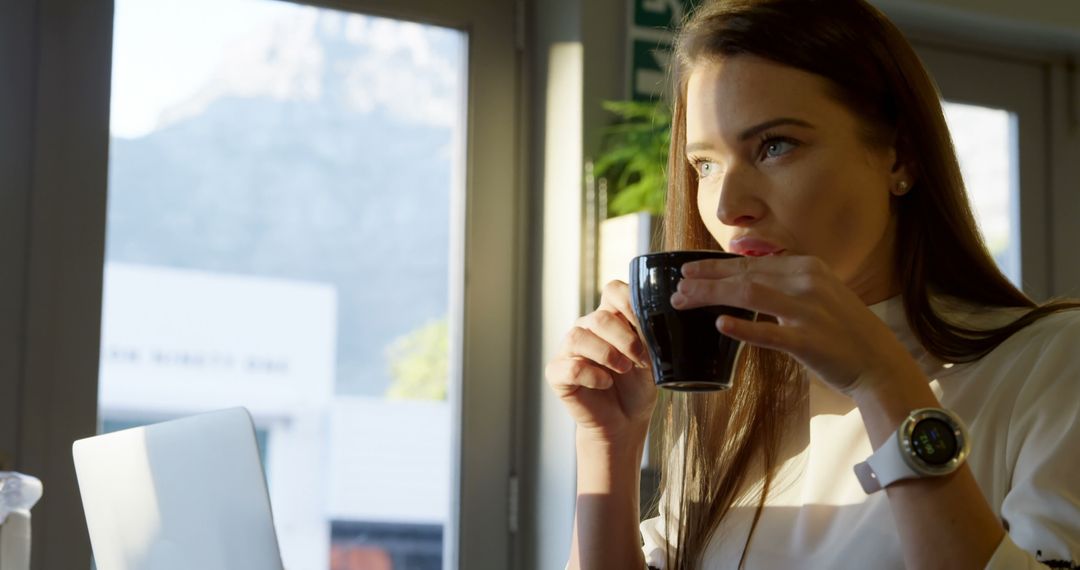 Businesswoman Drinking Coffee in Morning Sunlight by Window - Free Images, Stock Photos and Pictures on Pikwizard.com