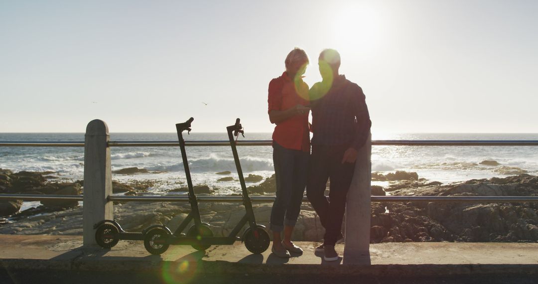 Senior Couple Embracing Near Ocean with Walkers at Sunset - Free Images, Stock Photos and Pictures on Pikwizard.com