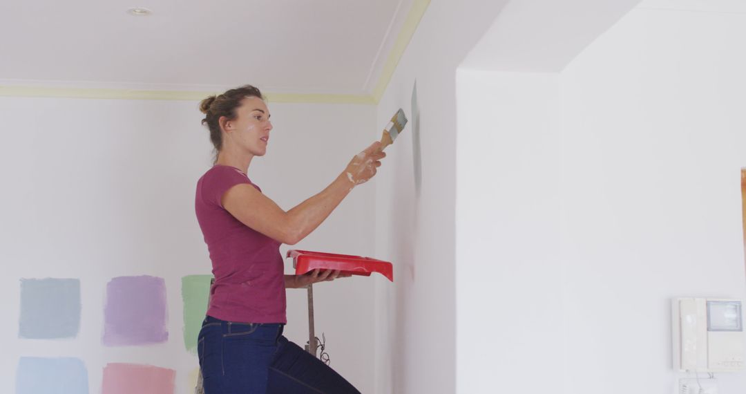 Woman Painting Interior Wall with Paint Samples in Background - Free Images, Stock Photos and Pictures on Pikwizard.com