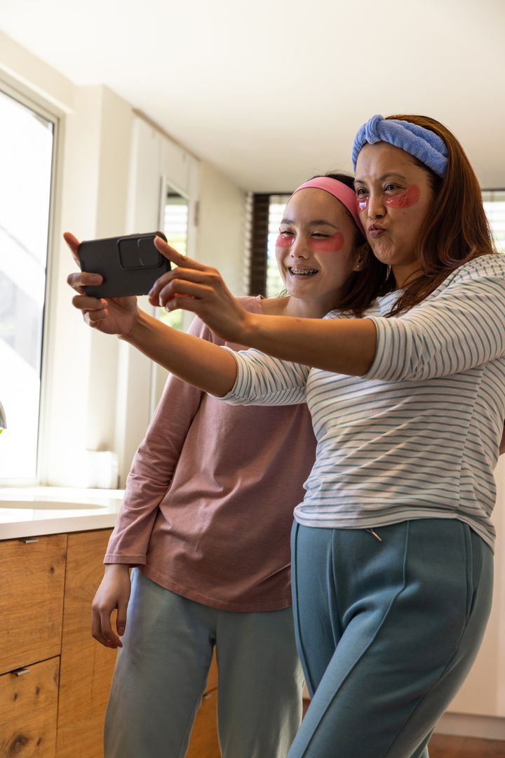 Mother and Daughter Taking Selfie in Kitchen with Skincare Patches