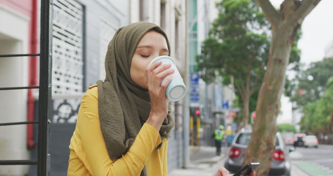 Young Woman in Hijab Enjoying Coffee Outdoors in Urban Setting - Free Images, Stock Photos and Pictures on Pikwizard.com