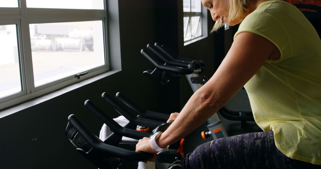 Senior Woman Exercising on Stationary Bike in Gym - Free Images, Stock Photos and Pictures on Pikwizard.com