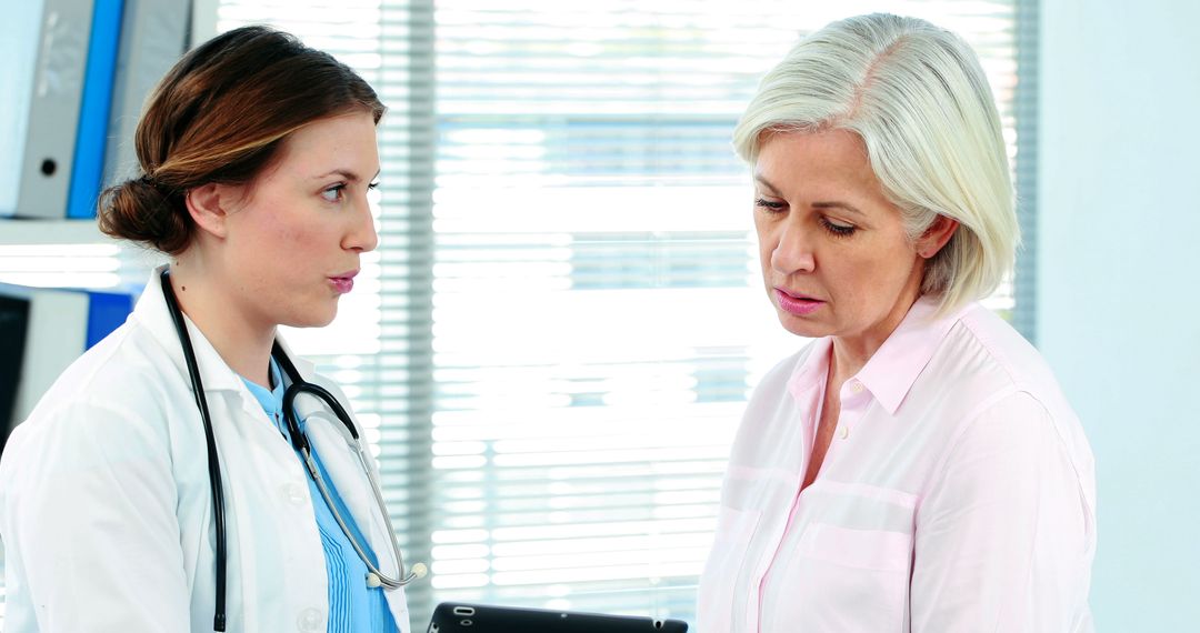 Doctor Discussing Health Records with Middle-Aged Patient in Clinic - Free Images, Stock Photos and Pictures on Pikwizard.com