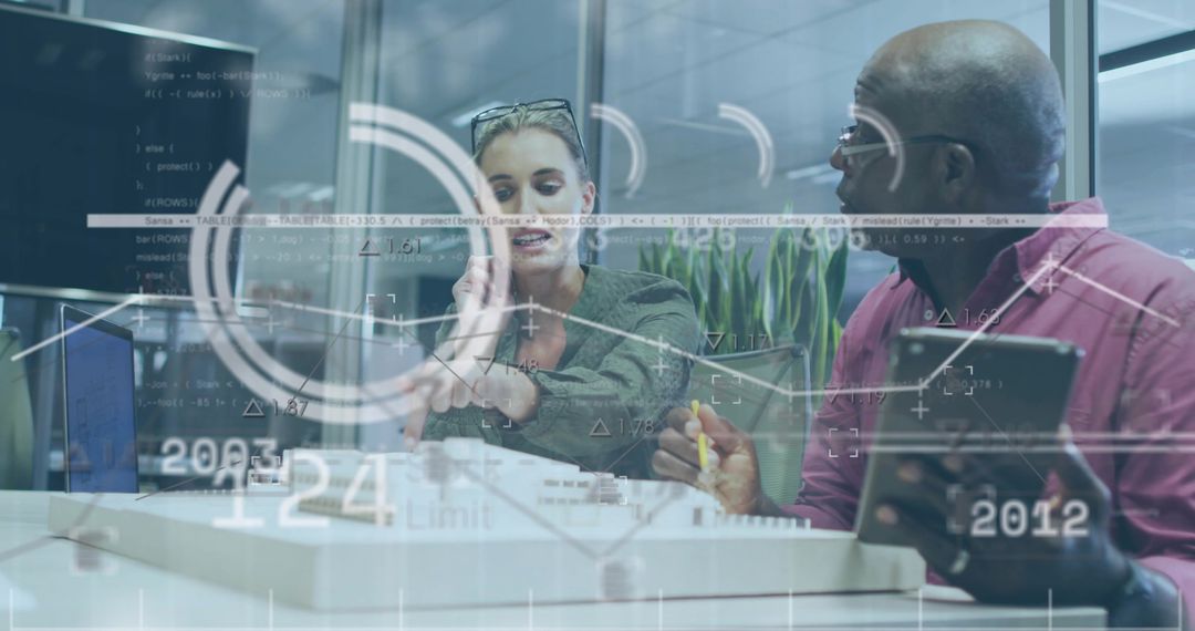 Two professionals collaborating on data analytics dashboard over tablet and laptop in modern office