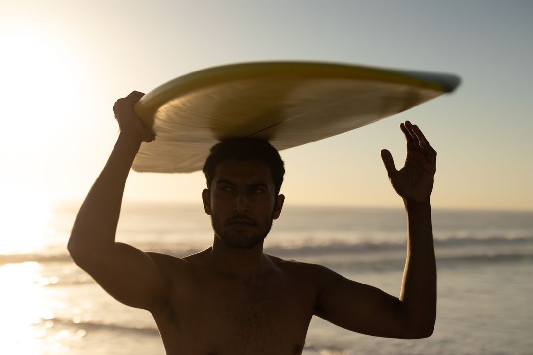 Young Man Holding Surfboard at Sunset Beach - Free Images, Stock Photos and Pictures on Pikwizard.com