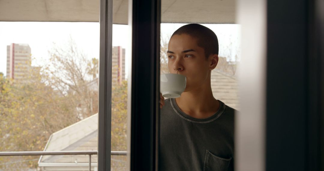 Young Man Drinking Coffee While Looking Through Window - Free Images, Stock Photos and Pictures on Pikwizard.com