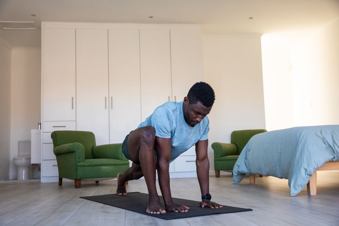 Man Performing Stretching Exercise on Yoga Mat in Cozy Bedroom